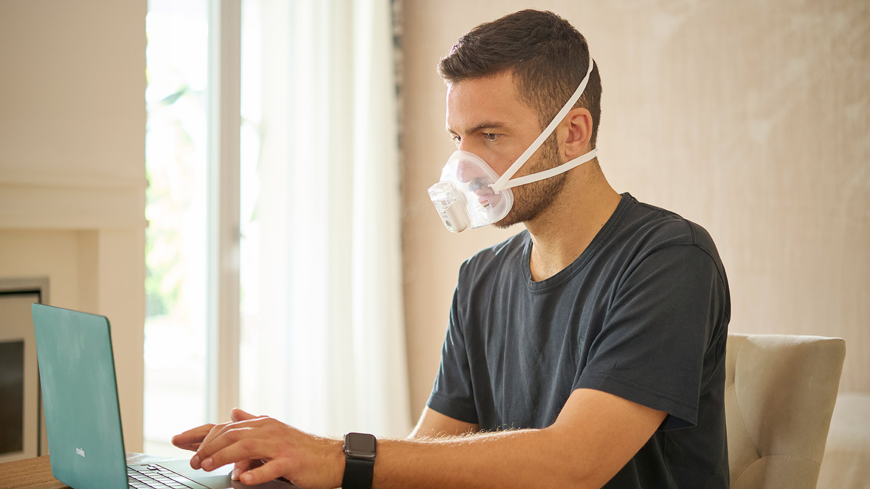 Uomo che lavora al laptop indossando l'aerosol mesh NuvitaMed