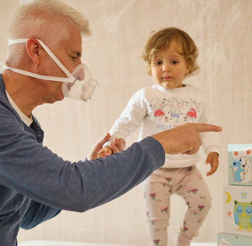 Nonno che gioca con la nipote mentre indossa l'aerosol